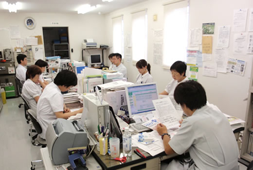 9人の薬剤師達が資料を読みながら打ち合わせをしている様子